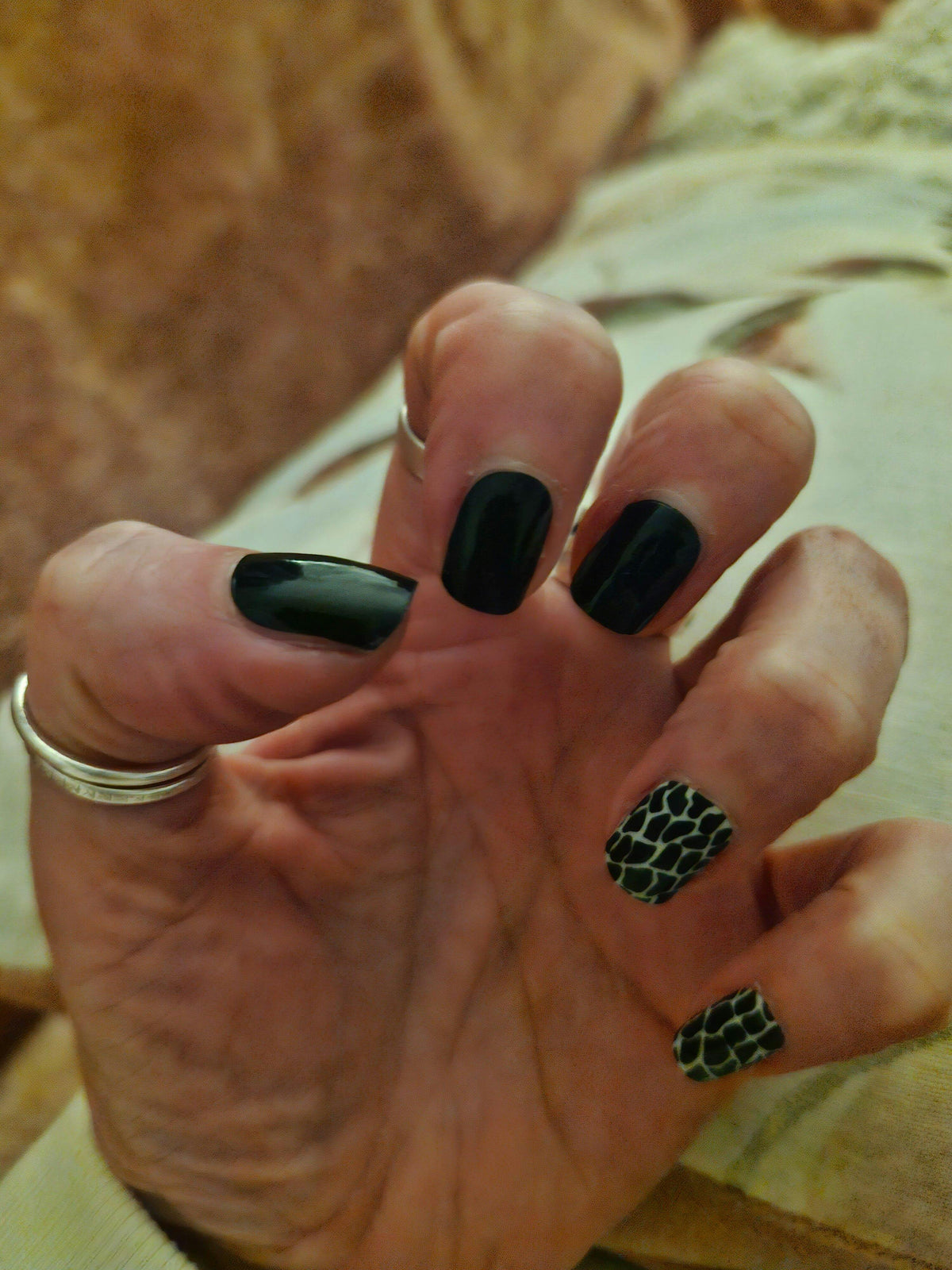 Glossy black nail wraps with two accent nails in green-black snakeskin print