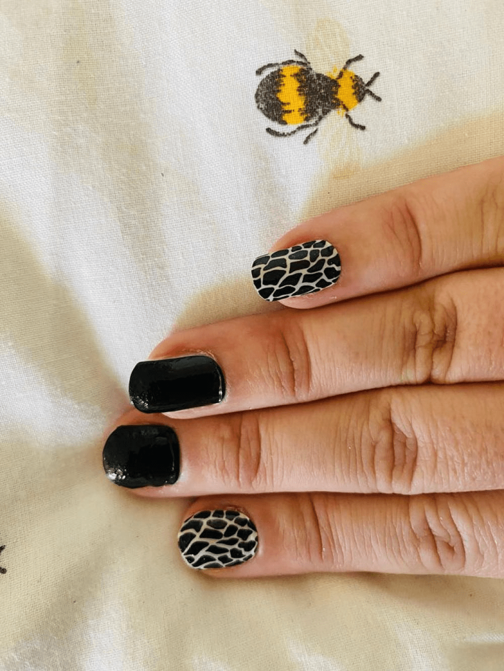 Animal print nail art with black and white giraffe pattern nail wraps on fingers