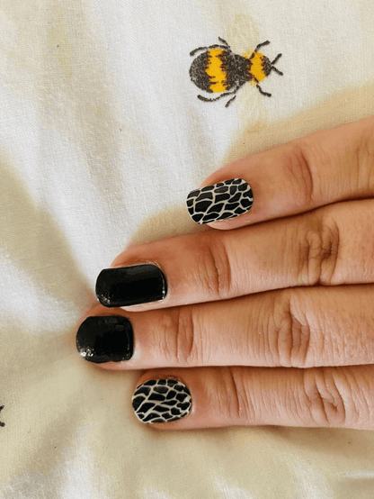 Animal print nail art with black and white giraffe pattern nail wraps on fingers