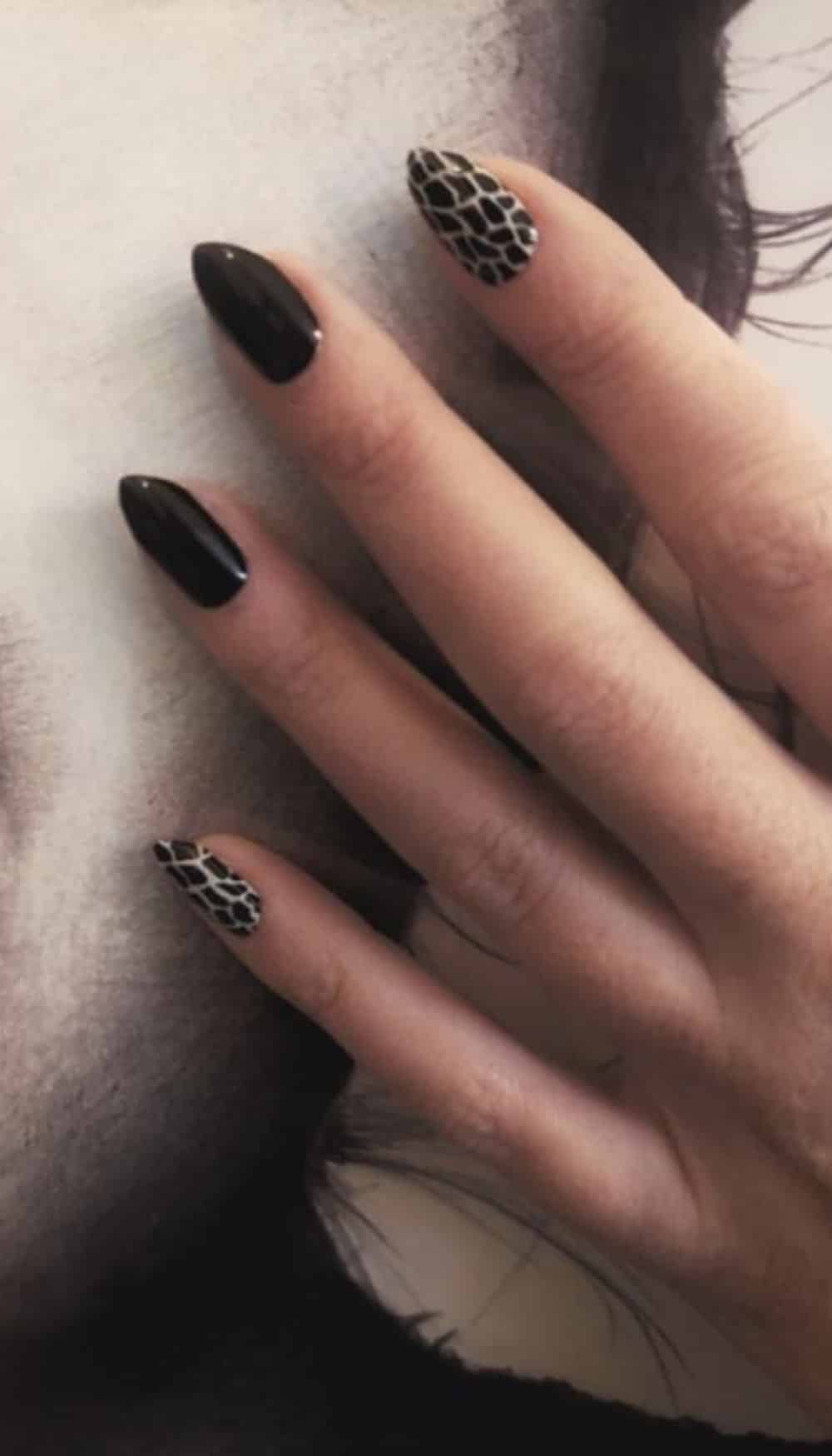 Black nail wraps with white giraffe print accent nail on hand manicure