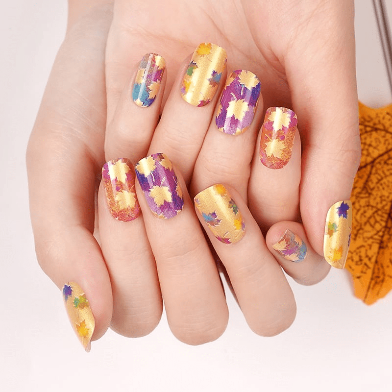 Colourful maple leaf nail wraps on both hands showing autumn seasonal nail art design