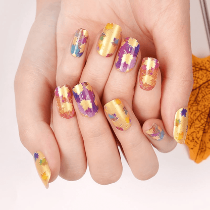Colourful maple leaf nail wraps on both hands showing autumn seasonal nail art design