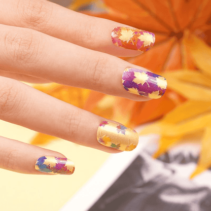 Orange maple leaf nail wraps on fingers showing autumn fall seasonal manicure design closeup