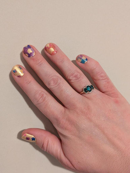 Colourful maple leaf nail art wraps displayed on hand with autumn foliage design