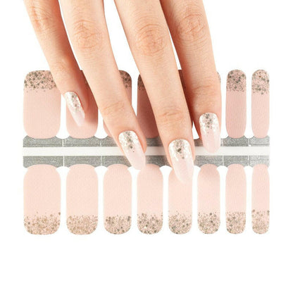 Hand wearing pink nail wraps with rose gold glitter ombre gradient design