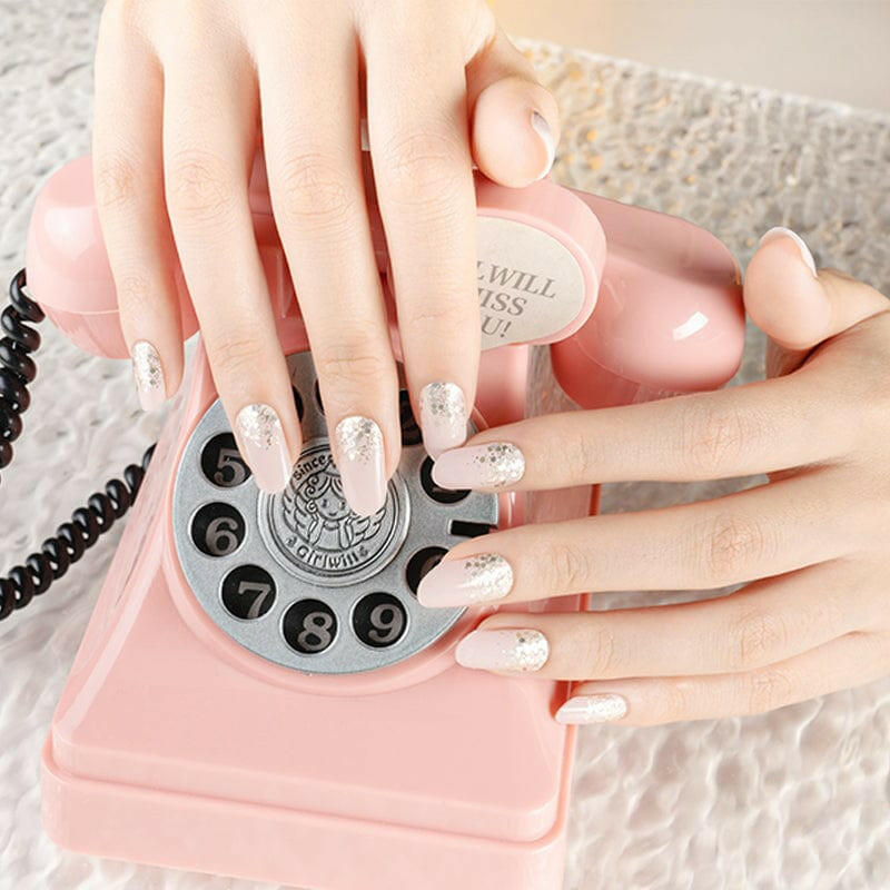 Hands with pink shimmer nail wraps holding vintage rotary phone for bridal manicure