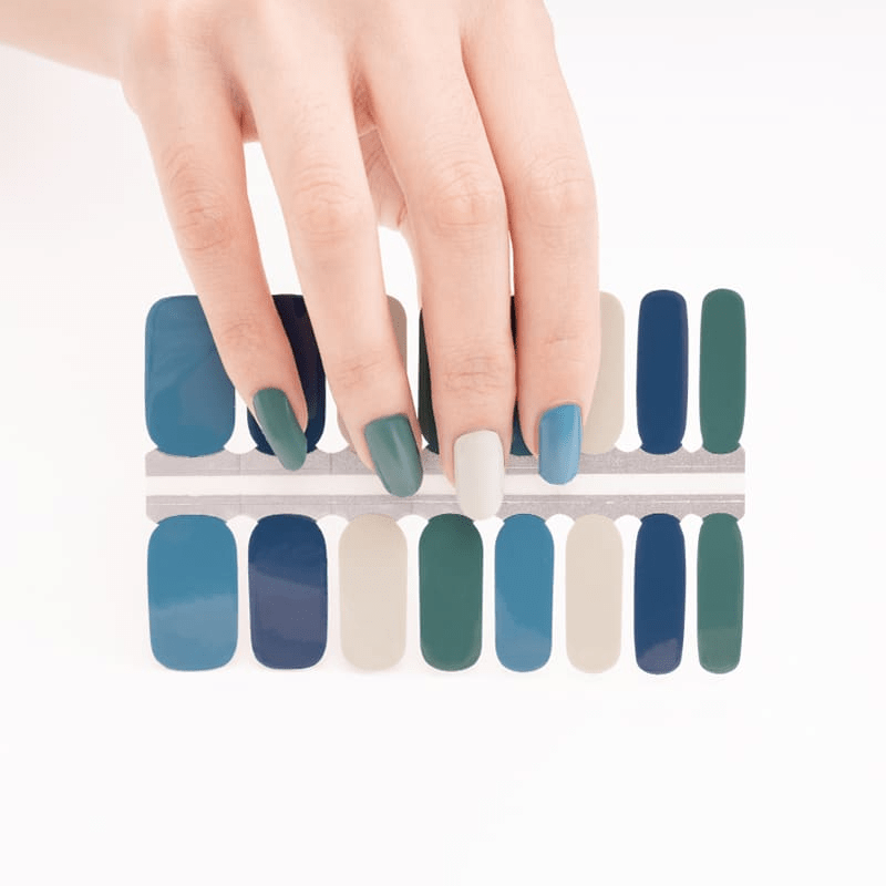 Hand selecting blue nail wraps from sheet showing application of non-UV nail wraps