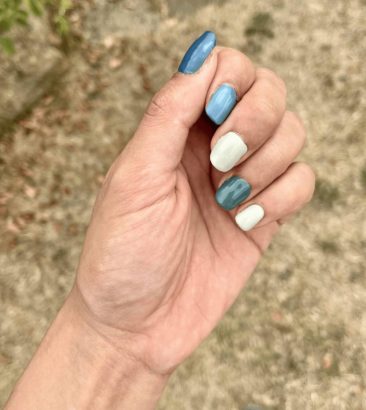 Matte blue green and cream non-UV nail wraps displayed on hand outdoors