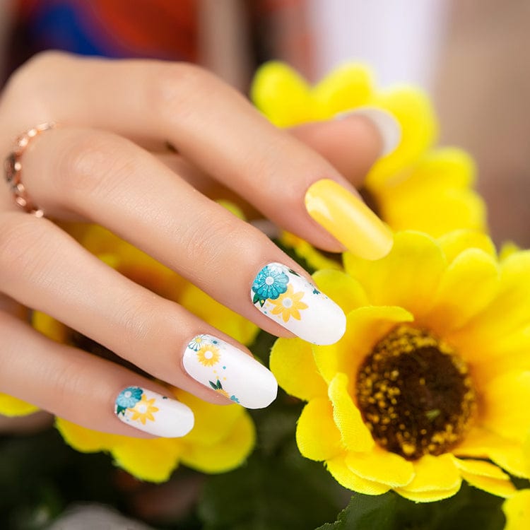 Hand wearing floral nail wraps with yellow and teal daisies on white background
