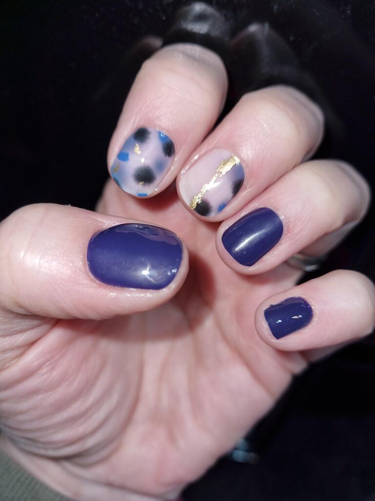 Blue terrazzo nail art with gold foil details and navy solid nails on hand