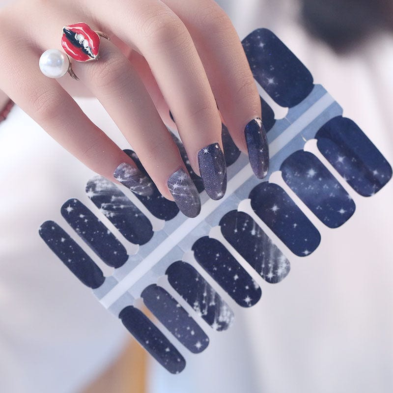 Hand holding black star nail wraps with silver celestial pattern design