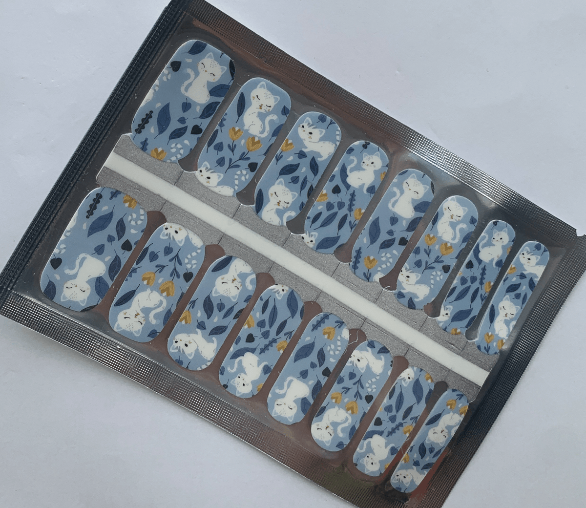 Blue non-UV nail wraps with white cats and flowers in packaging sheet