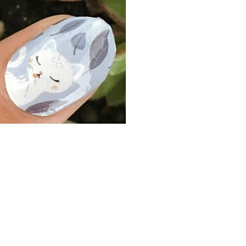 Blue nail wrap with white cats and floral patterns on hand for cute nail art