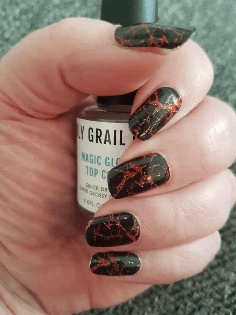 Black marble nail wraps with copper veins on hand holding nail glue bottle