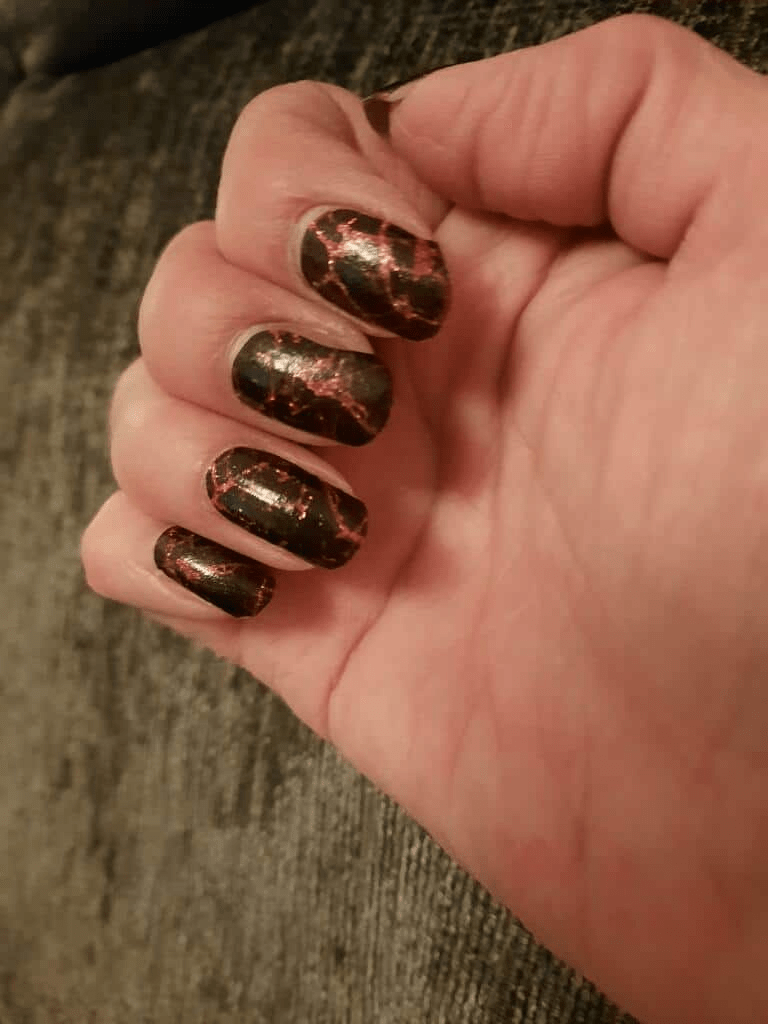 Black nail wraps with metallic copper-red crackle foil pattern, glossy finish