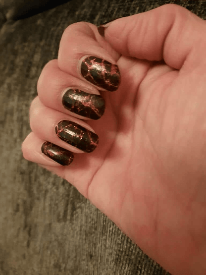 Black nail wraps with metallic copper-red crackle foil pattern, glossy finish