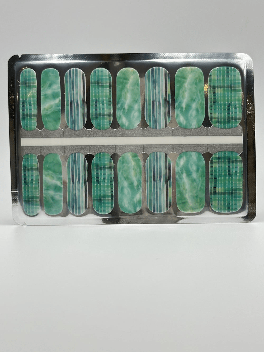 Mint green nail wraps with striped and watercolour patterns in packaging