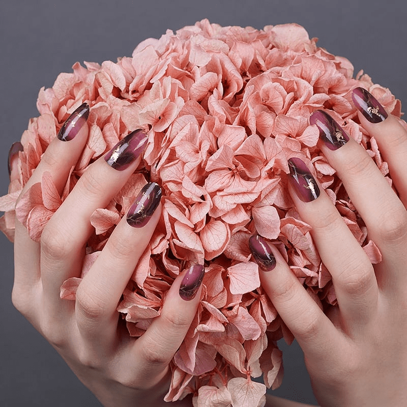 Chrome burgundy marble nail art on hands holding pink rose petals manicure inspiration