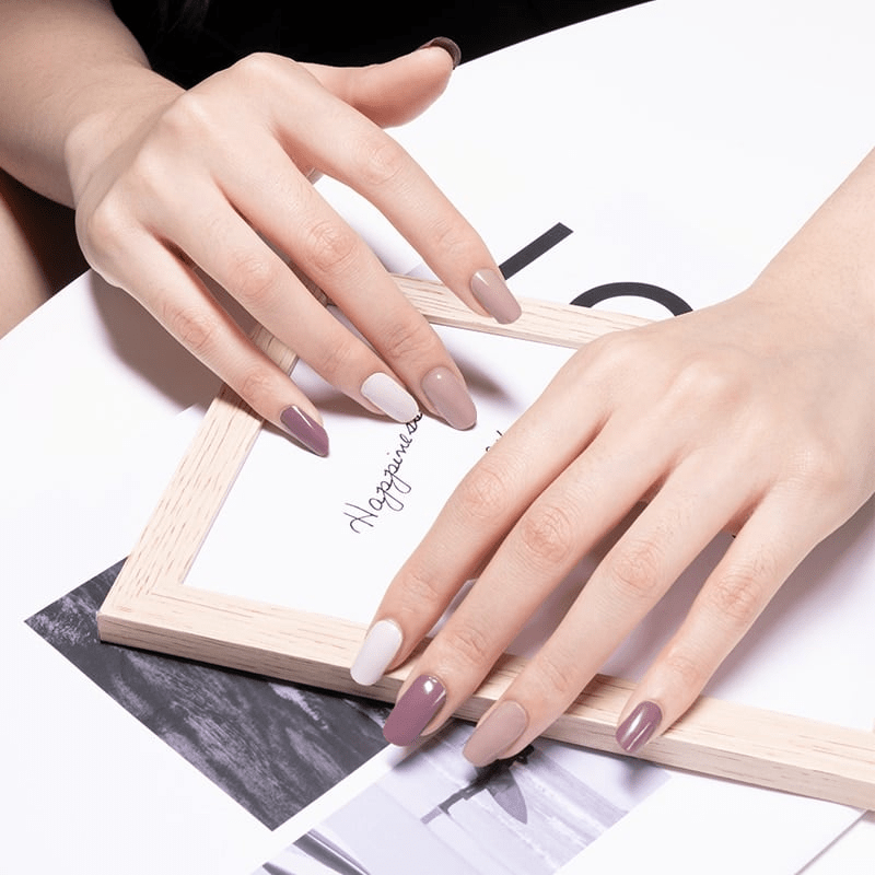 Hands with mocha brown nail wraps creating professional at-home manicure look on neutral background