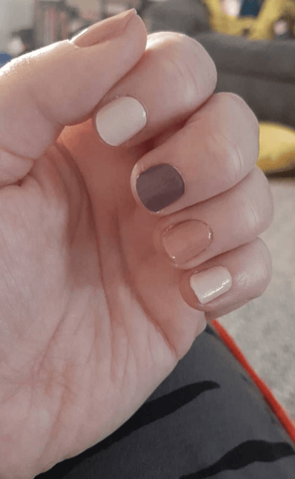 Close-up of short nails with Holy Classics nail wraps in mocha brown, cream and nude shades, glossy finish.
