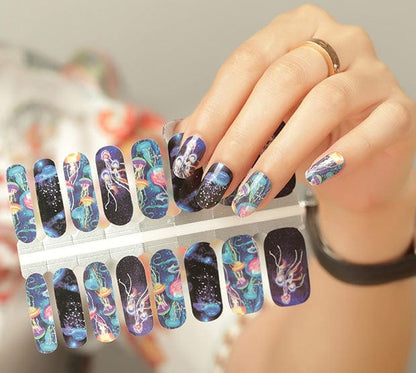 Hand holding sheet of underwater jellyfish nail wraps with blue holographic marine designs
