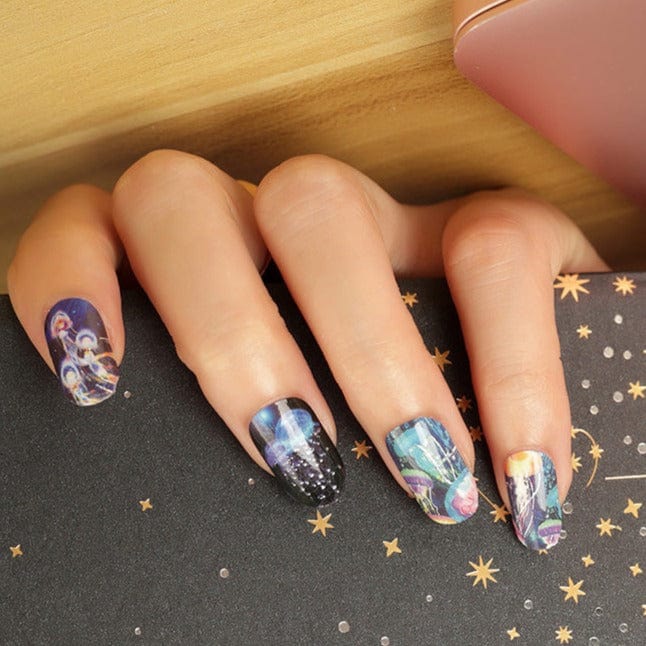 Ocean themed nail wraps on hand displaying blue jellyfish patterns with holographic finish