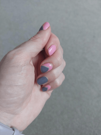 Pink and grey geometric nail wraps on hand showing modern abstract nail art design