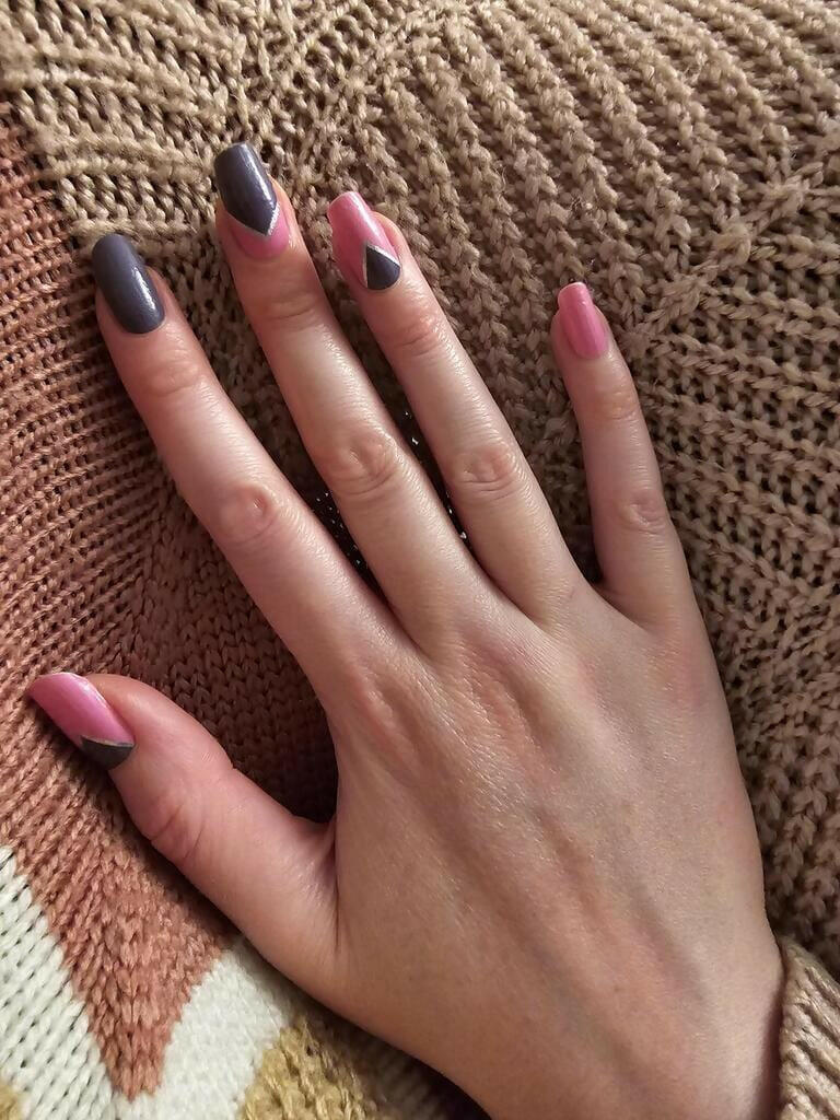 Two hands displaying pink and grey geometric nail wraps with modern triangular nail art