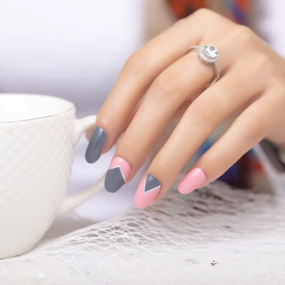 Hand holding white mug showing pink and grey minimalist nail wraps geometric design