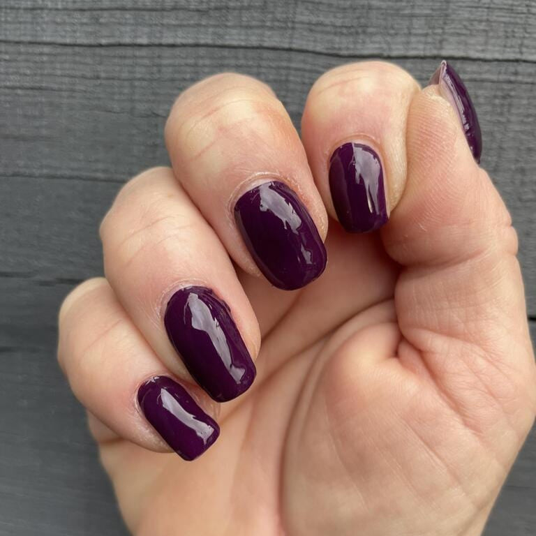 Deep mulberry purple glossy nail wraps on short, natural-shaped nails