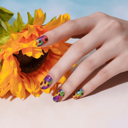 Hand with bright sunflower nail art wraps beside yellow sunflower showing floral nail design