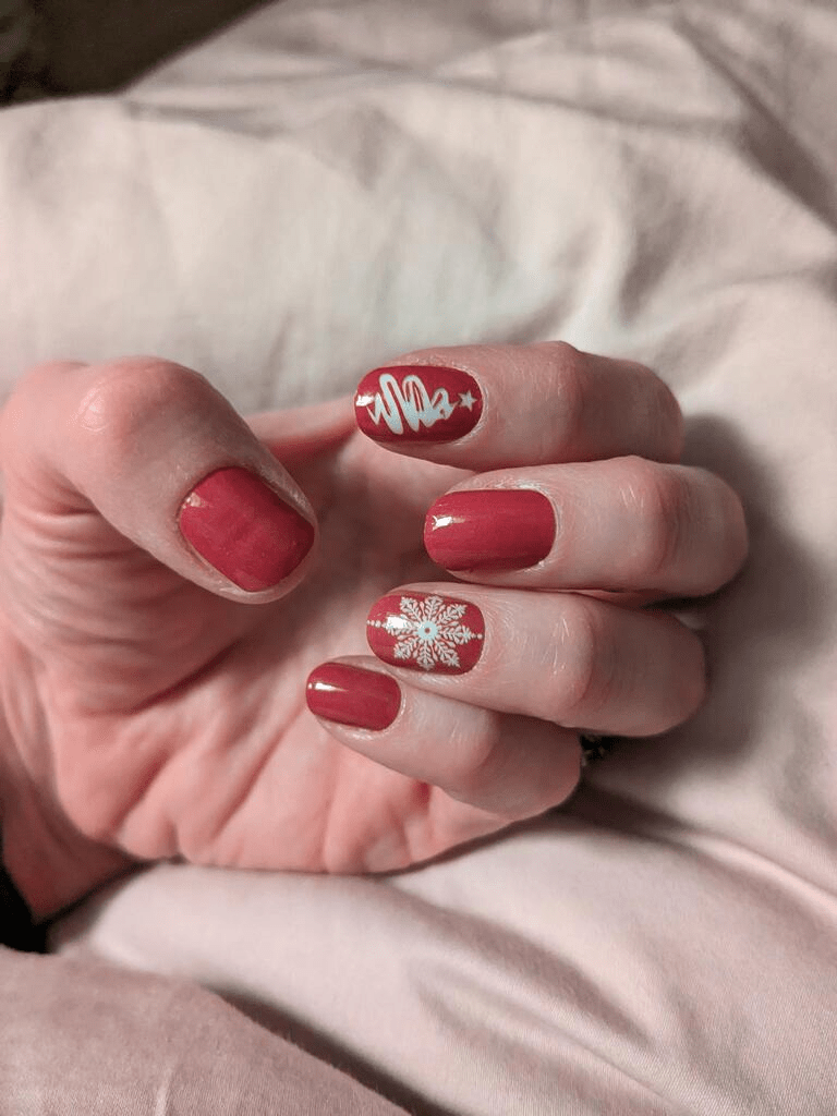 Red glossy Christmas nail wraps with white snowflakes worn on hand