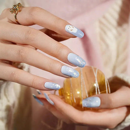 Holiday manicure featuring blue glitter nail wraps with winter snowman nail art
