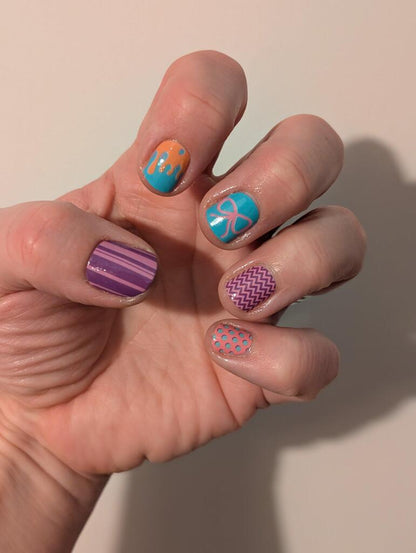 Colourful geometric nail wraps on hand featuring purple chevron turquoise palm tree patterns for nail art