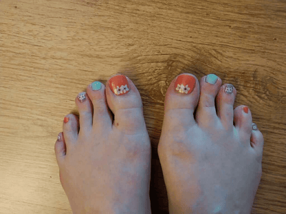 Pedicure nail wraps on feet showing coral orange green purple orchid floral design
