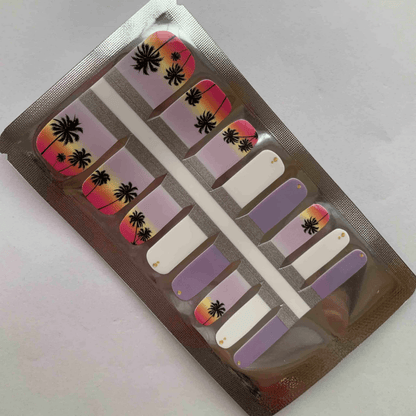 Purple and coral sunset gradient pedicure nail wraps with black palm tree silhouettes in package