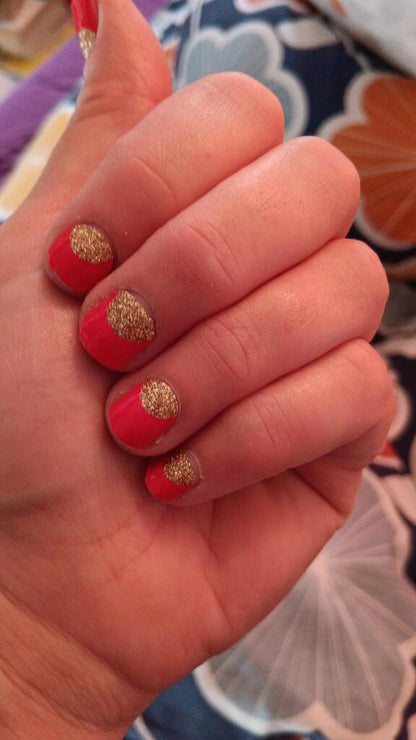 Red nail wraps with gold glitter accent tips displayed on fingers showing manicure results