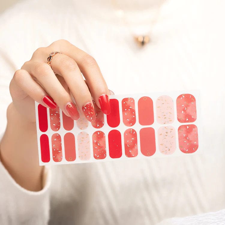 Hand displaying red marble nail wrap sheet with mixed patterns and textures