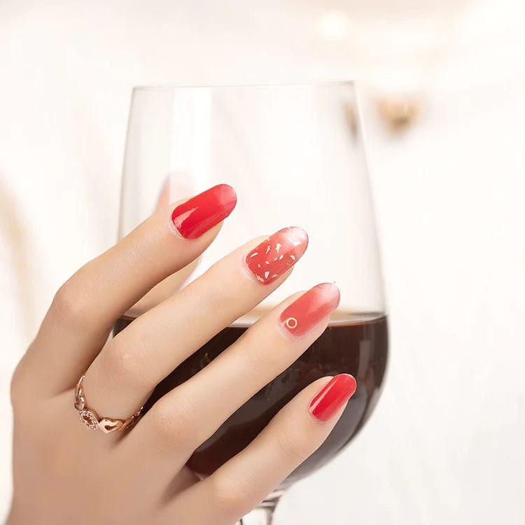 Red marble nail wraps on hand holding wine glass showing glossy finish