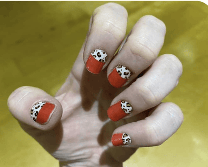 Hand wearing red nail wraps with black and white leopard print tips