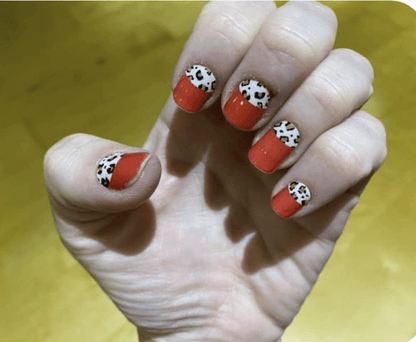 Hand displaying red nail wraps with leopard print French tip manicure design