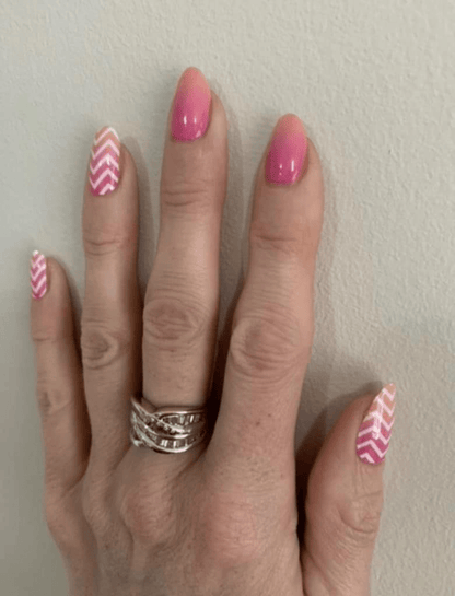 Pink glossy nail wraps with white chevron stripe pattern on accent nails