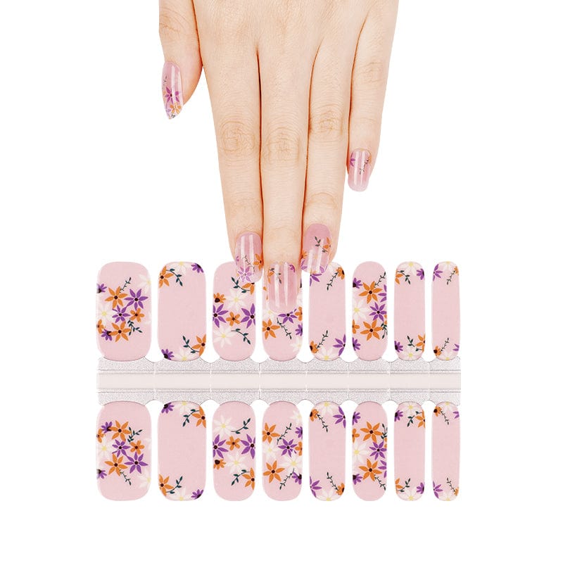 Hand selecting from pink pansy nail wraps sheet with purple and orange floral pattern
