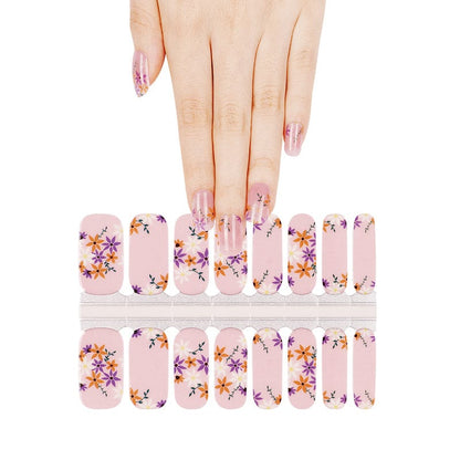 Hand selecting from pink pansy nail wraps sheet with purple and orange floral pattern