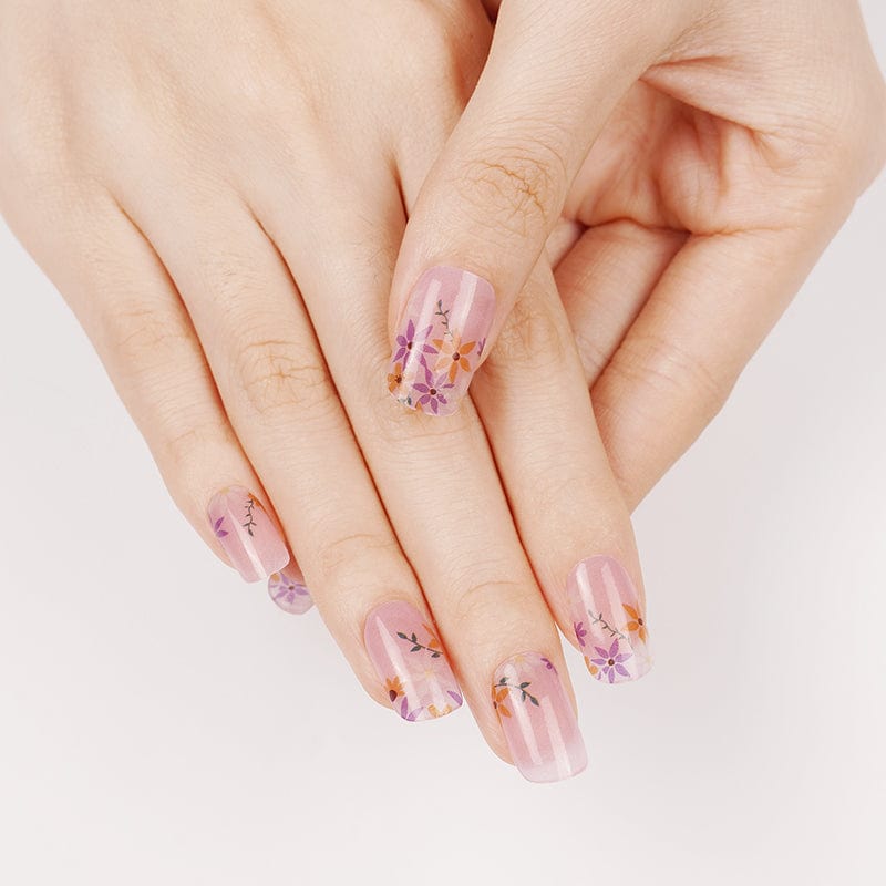 Sheer pink nail wraps with subtle stripes and purple-orange pansy floral accents