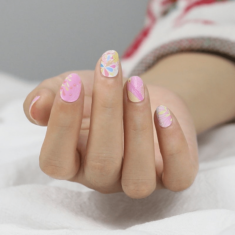 Pink floral nail wraps on hand with botanical patterns and soft pastel designs