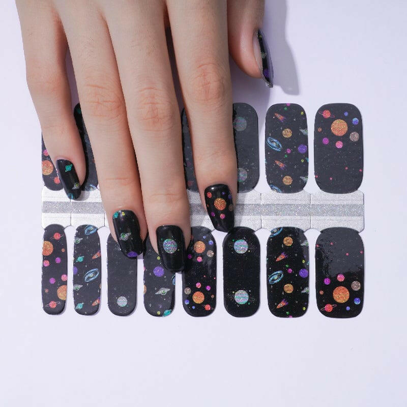 Black nail wraps with colourful planet and star space pattern on hand with application sheet