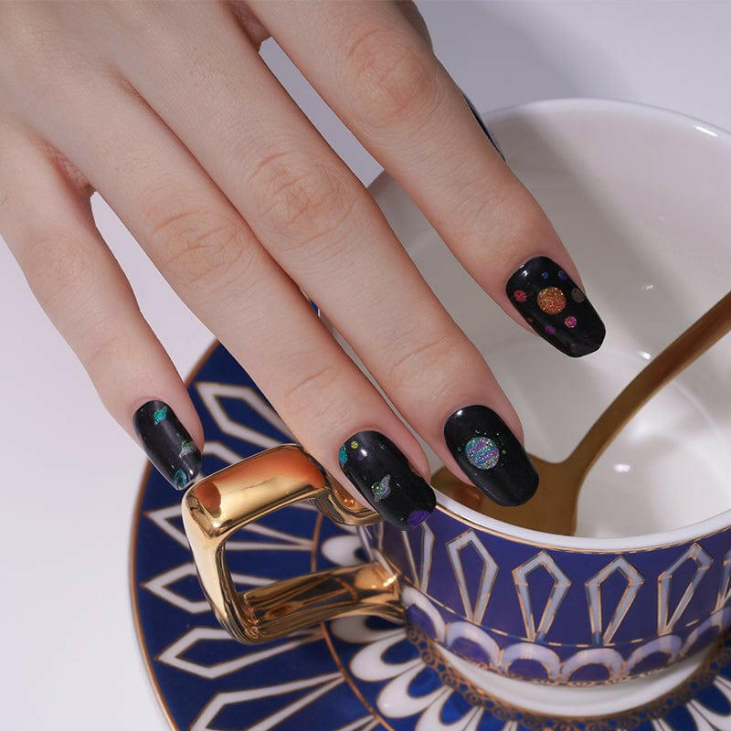 Black nail wraps with glittery multicoloured planet and star constellation design