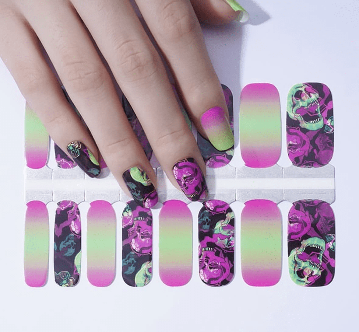 Hand wearing pink ombre and floral skull nail wraps with gothic design