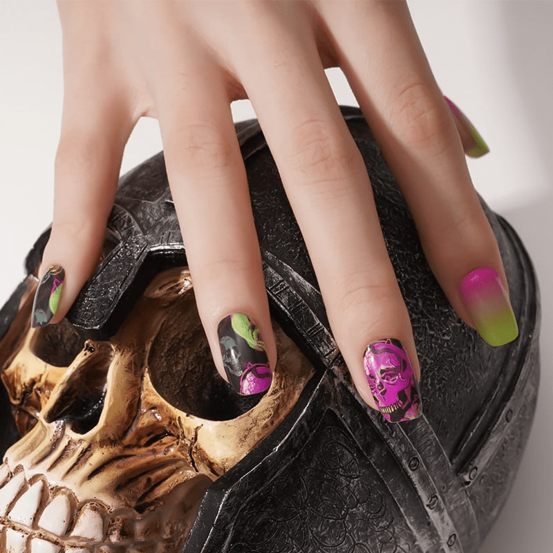 Hand over skull prop displaying spooky ombre nail wraps with pink florals